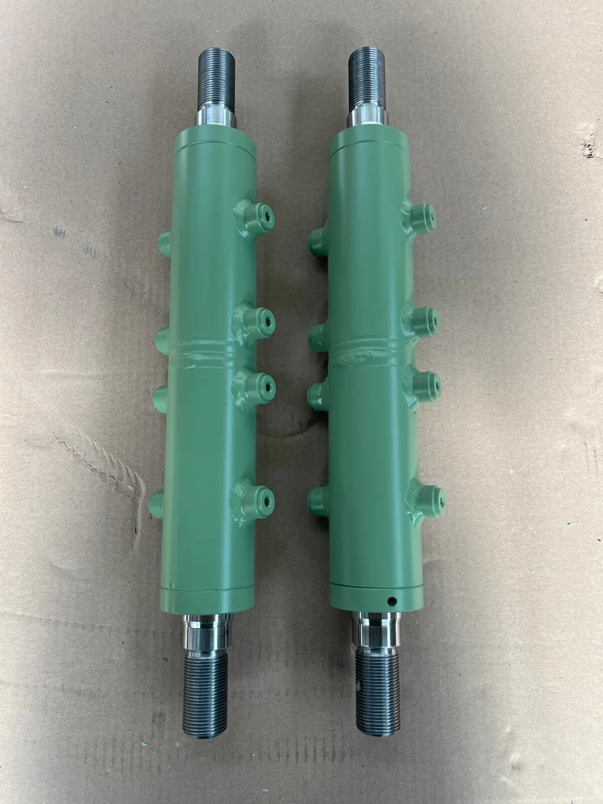 Zwei fertige Hydraulikzylinder in grüner Lackierung aus eigener Fertigung — Foltas Hydraulik